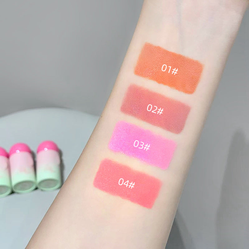 Lipstick swatches on a person's arm with labeled colors and lipsticks in the background.