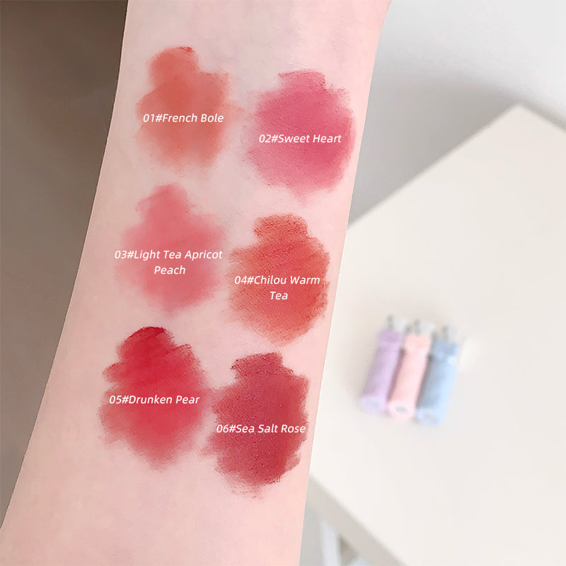 Lipstick swatches on a person's arm with color names and codes.
