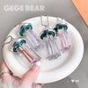 Clear lip glosses with colorful tops on a white plate, held by a hand.