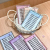 Multiple boxes of false eyelashes on a wooden surface with a woven basket.