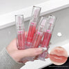 Hand holding four lip glosses with a close-up of lips wearing the product on a white background.