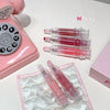 Pink vintage phone and lip glosses on a white surface
