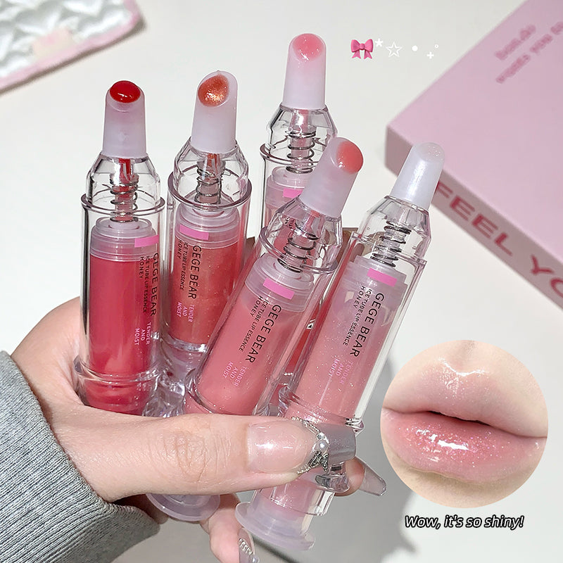 Set of lip glosses held by a hand with a close-up of glossy lips.