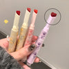 Four lipsticks held in a hand with a gray background