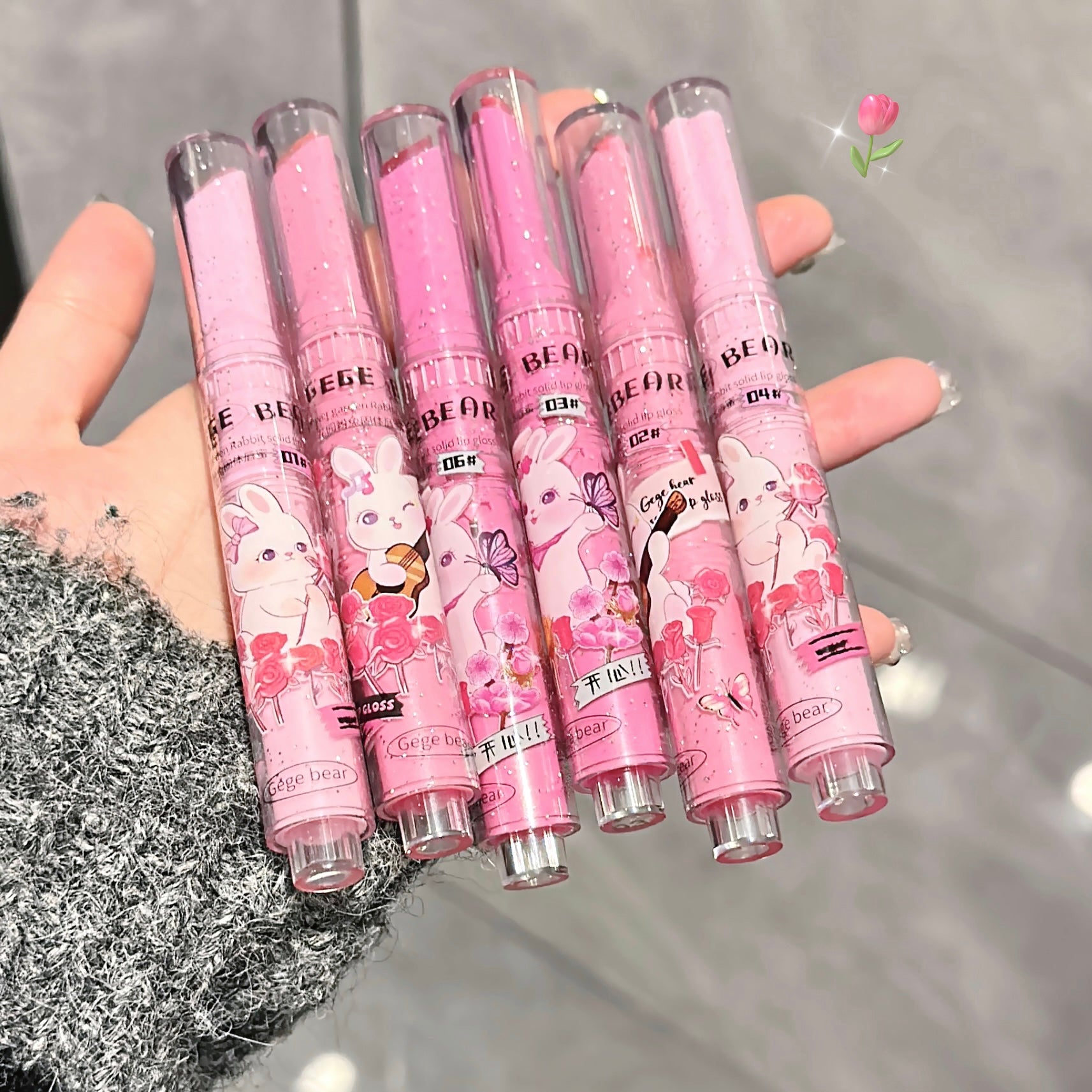 Set of pink cartoon-themed pens held by a hand against a neutral background