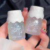 Two small bottles of 'Gege bear' lip gloss held in a hand against a dark background.
