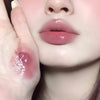 Close-up of a person's lips with a hand holding a lip balm.