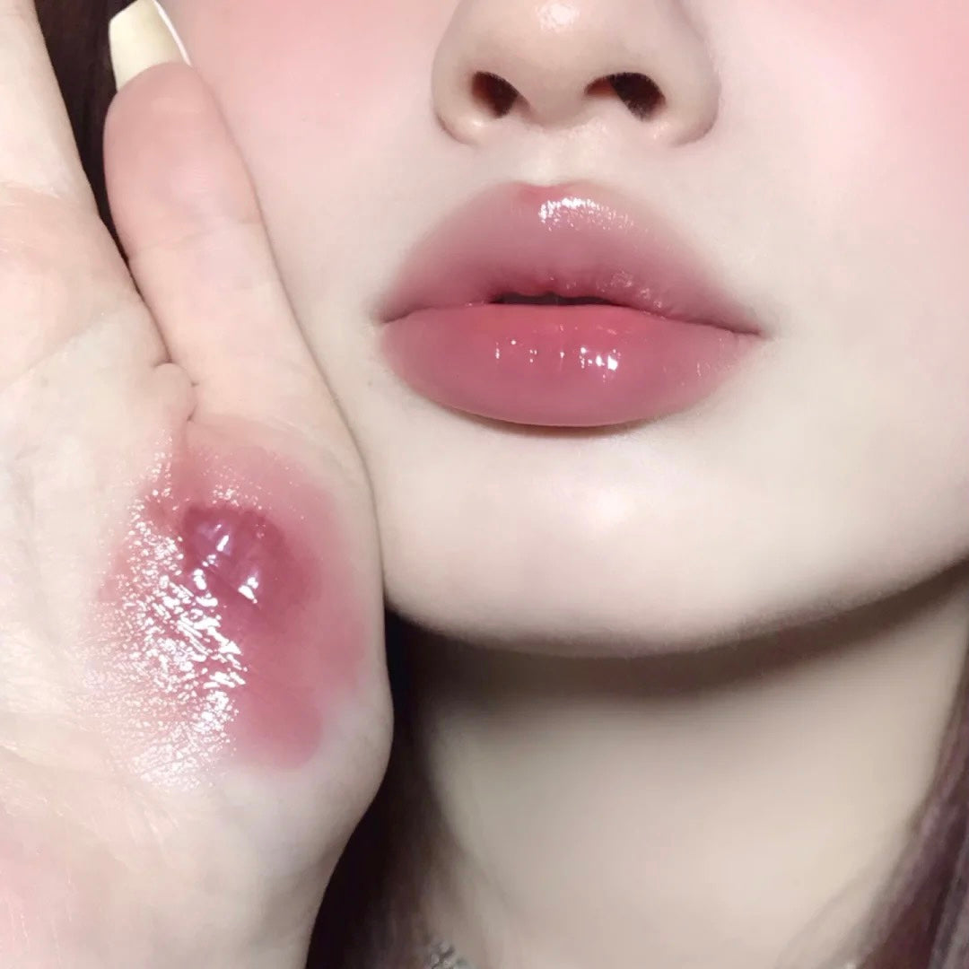 Close-up of a person's lips with a hand holding a lip balm.
