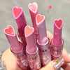 Set of pink lip balms with heart-shaped caps held by a hand.