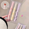 Set of three pastel-colored lip balms in a clear packaging case held by a person.