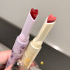Two lip glosses with heart-shaped caps held by a hand against a neutral background