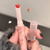 Hand holding a small pink lipstick with a heart-shaped cap against a neutral background