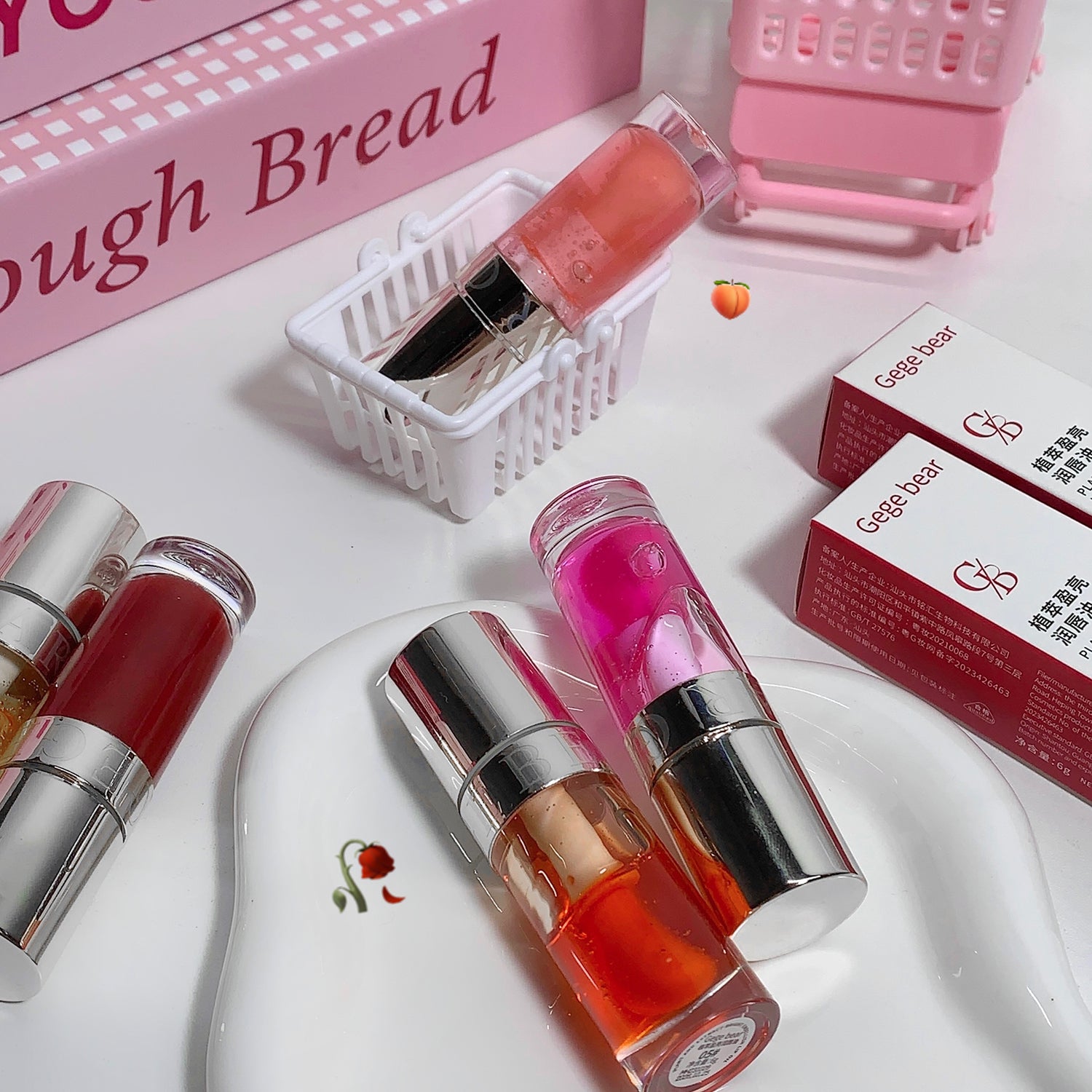 Lip glosses on a white surface with 'Gegg bread' packaging in the background