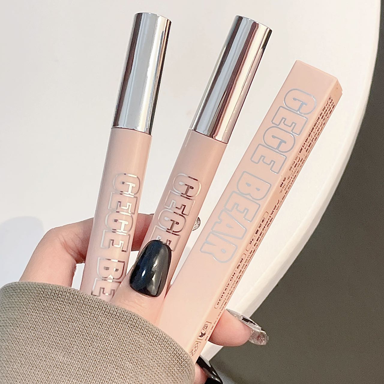 Two makeup products with 'GEGE BEAUTY' branding held by a hand against a neutral background.