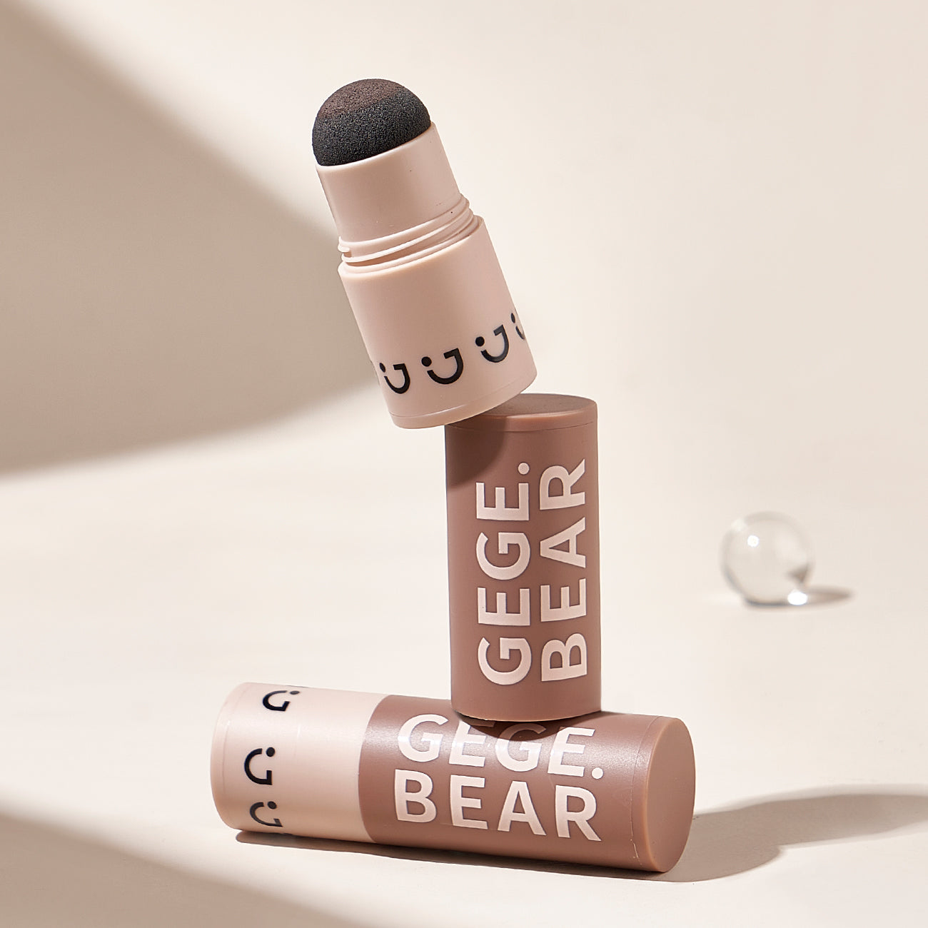 Makeup stick with applicator and 'GGE.BEAR' branding on a beige background