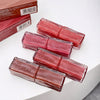 Four lip glosses with 'GE BEAR' branding on a white surface, with two boxes in the background.