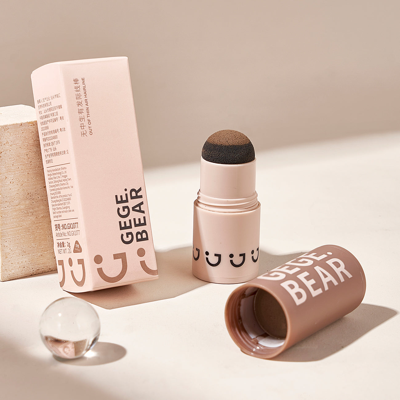 Makeup stick with smiley face design and packaging on a neutral background
