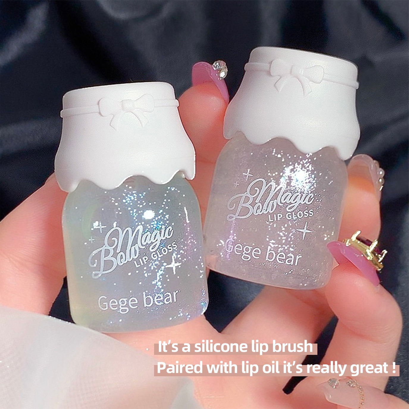 Two small bottles of 'Ball Magic' lip gloss held by a hand with a dark background.