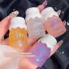 Four small lip gloss containers with 'Belle Magic' branding held in a hand against a dark background.