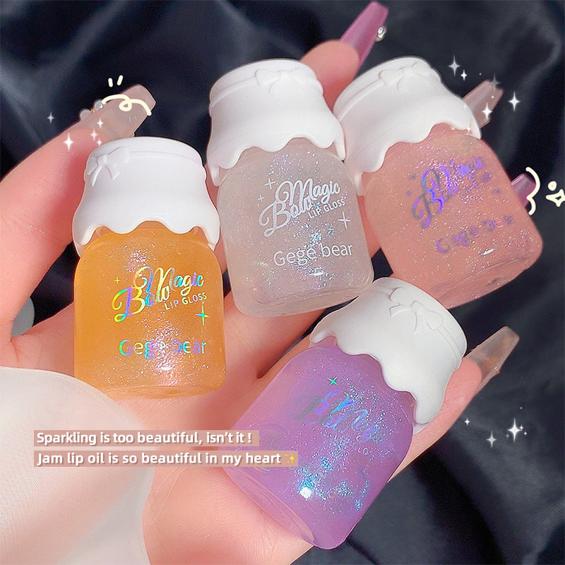 Four small lip gloss containers with 'Belle Magic' branding held in a hand against a dark background.