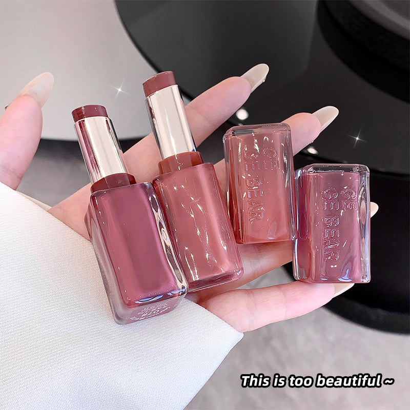 Two lipsticks and two nail polishes held in a hand with a blurred background