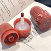 Open coral-colored lip balm with visible brand name on a book page background