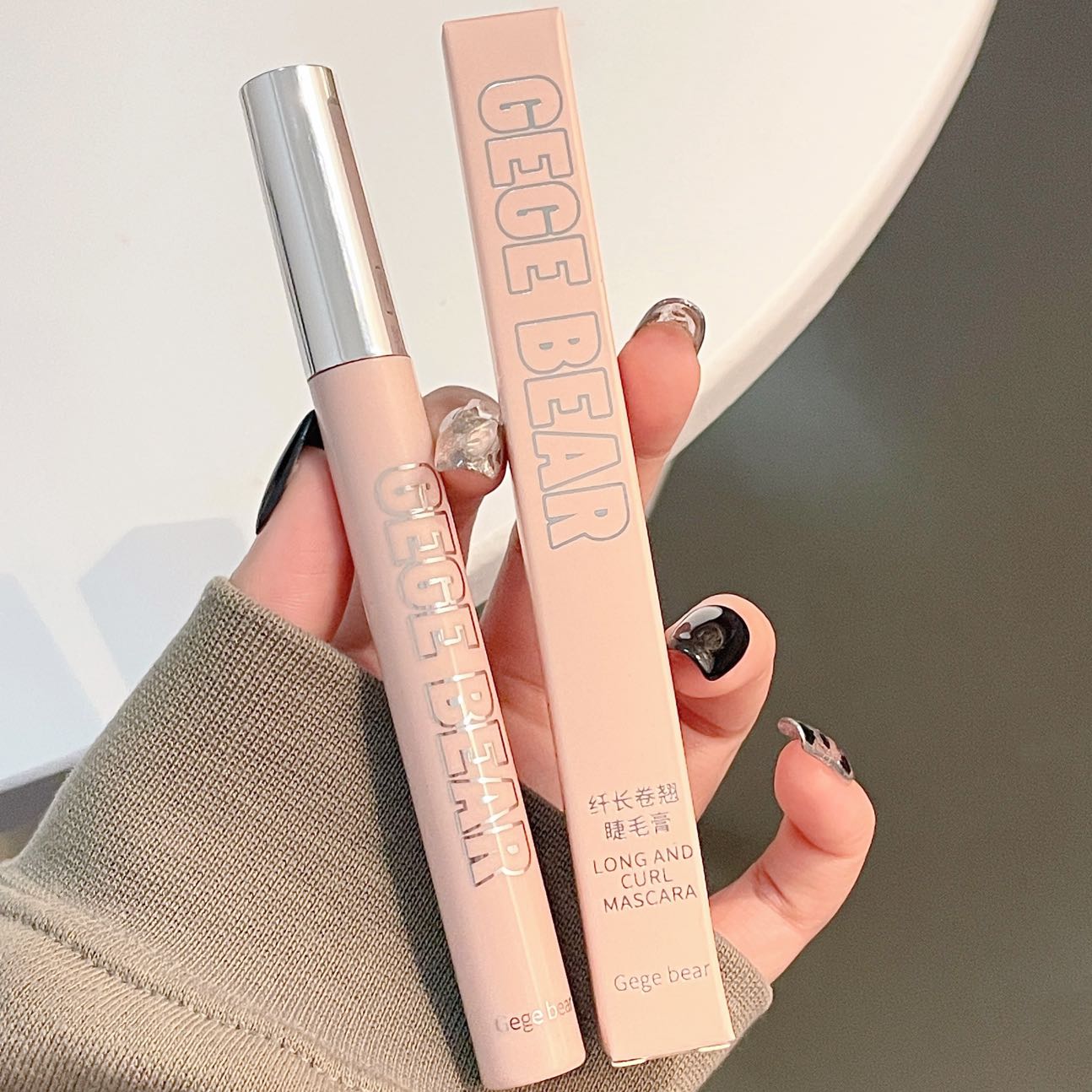 Gige Bear mascara and eyeliner held by a hand against a neutral background