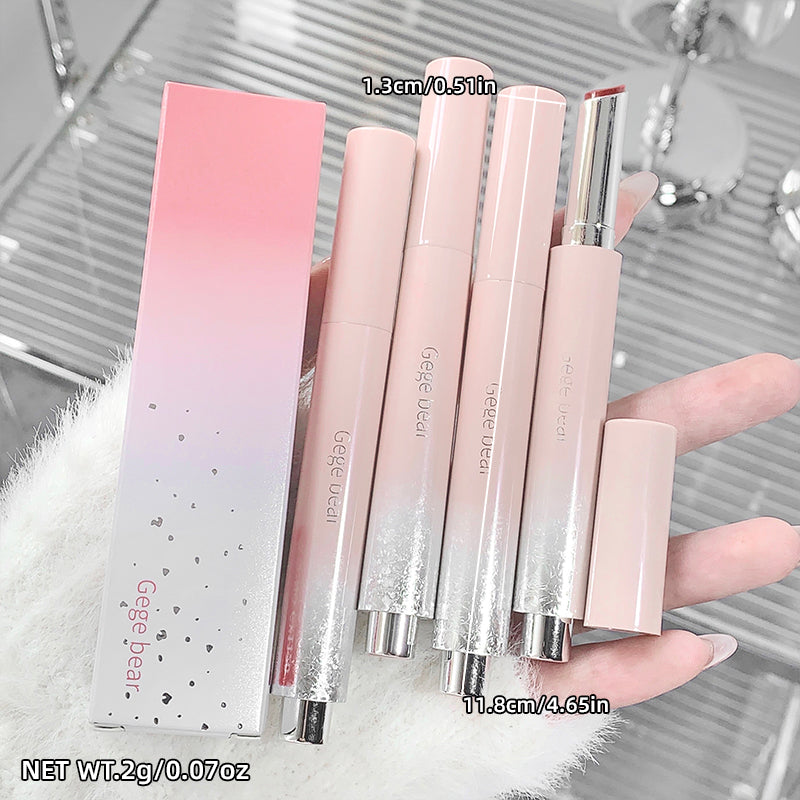 Set of pink lip glosses with packaging held by a hand, against a blurred background.